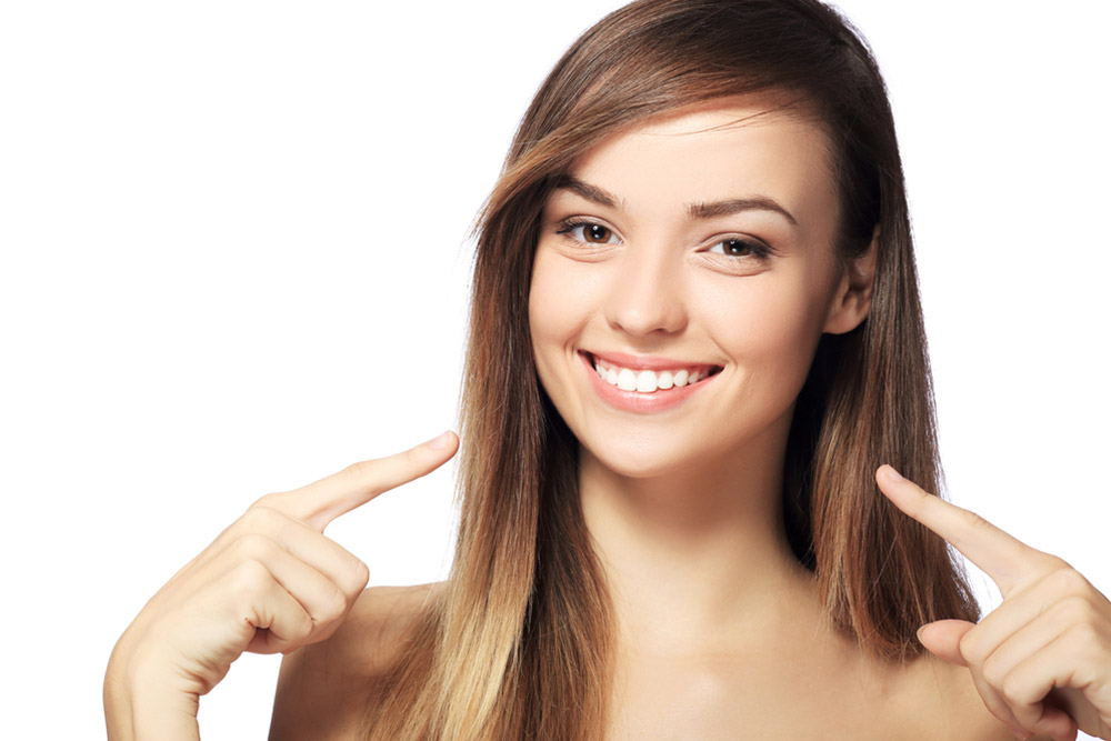 Woman with beautiful smile pointing on her teeth